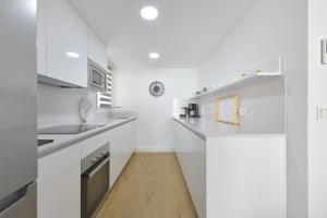 a white kitchen with white cabinets and a wooden floor at Apartamento de lujo vista mar en Torrox Costa in Torrox Costa