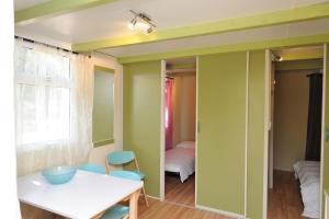 維琪奧港的住宿－CAMPING LES ILOTS D'OR，一间拥有绿色墙壁和桌椅的用餐室