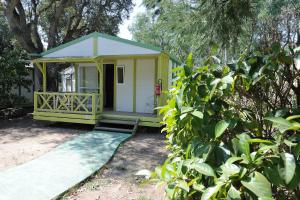 CAMPING LES ILOTS D'OR في بورتو فيكيو: منزل أصفر صغير مع شرفة في الفناء