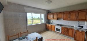 a kitchen with wooden cabinets and a window at Carnota PLAYA a 100 metros in Carnota