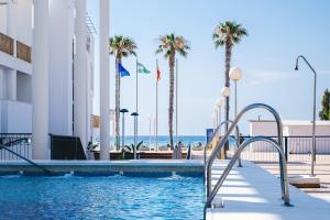 a swimming pool with palm trees and the beach at Hotel Don Ignacio in San José