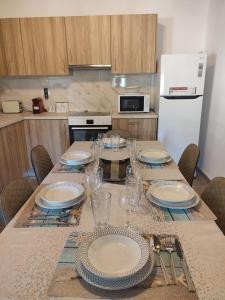 einen Tisch mit Tellern und Gläsern darauf in der Küche in der Unterkunft Villa Jimmy, Pilona Village in vlicha