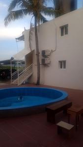 a swimming pool in front of a building with a palm tree at Ivan Garden B&B in Hengchun