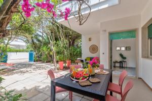 una sala da pranzo con tavolo nero e sedie rosa di Villa Coralia a 20mt dalle spiagge a Torre Santa Sabina