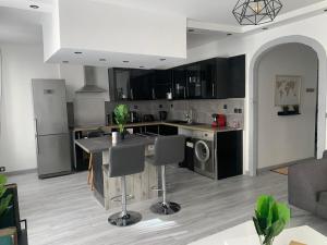 馬賽的住宿－« Le Madeleine »，一间厨房,配有黑色橱柜和一个带椅子的厨房岛