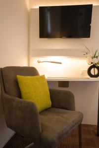 a chair with a yellow pillow and a tv on a wall at Altdeutscher Hof Beckord in Gütersloh