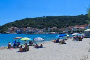 a group of people sitting on a beach with umbrellas at Il Rifugio del Pescatore in Marciana Marina
