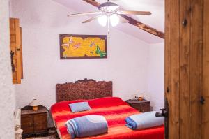 a bedroom with a red bed and a ceiling fan at Casa Cueva Alegría in Valdeganga