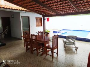 a dining room with a table and chairs and a pool at Casa em Maragogi in Maragogi