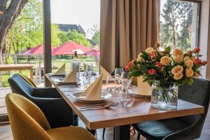 a wooden table with a vase of flowers on it at Hotel Müllers-Weiden in Eschwege