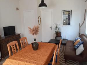 a dining room with a table and a couch at Maisonnette proche de la plage in Tarnos