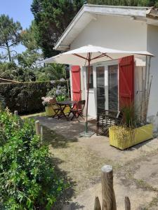 une terrasse avec une table et un parasol dans l'établissement Maisonnette proche de la plage, à Tarnos
