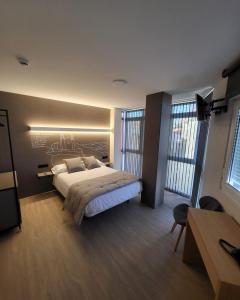a bedroom with a large bed and two windows at HOSTAL HABITAT MUXIA II in Muxia