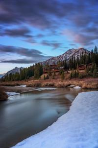 einen Fluss mit Schnee vor Häusern und Bergen in der Unterkunft Mount Engadine Lodge in Kananaskis Village