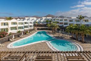 a swimming pool with palm trees and buildings at Apartamentos LIVVO Morromar in Puerto del Carmen