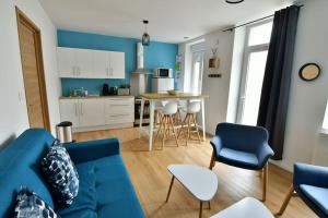 a living room with a blue couch and a kitchen at Le 46 - T2 rénové, confortable proche centre-ville in Montluçon