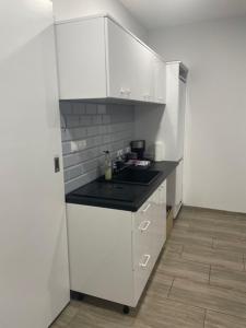a kitchen with white cabinets and a black counter top at Yacht Club Apartamenty in Radzyń