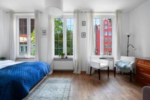 a bedroom with a bed and a desk and windows at Elite Apartments Hamptons Old Town in Gdańsk