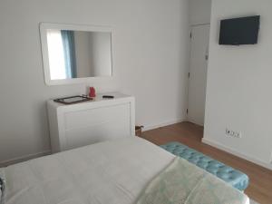 a white bedroom with a bed and a mirror at Brava in Vila Franca do Campo