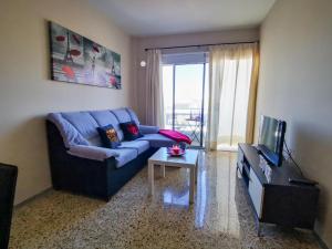a living room with a blue couch and a tv at Puesta de Sol Rentals 3AJ in Playa de San Juan