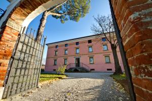 una entrada a un edificio rosa con una puerta en Villa Butussi - L'ospitalità del Vino, en Corno di Rosazzo