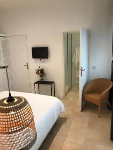 um quarto com uma cama, uma cadeira e uma televisão em Maison Boussingault em Avignon
