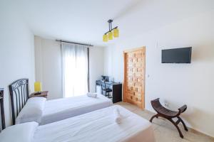 ein Hotelzimmer mit zwei Betten und einem Fernseher in der Unterkunft La Posada de la Gula in Jarandilla de la Vera