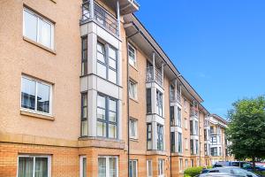 a tall brick building with cars parked in front of it at Bannermill Place Apartments - Grampian Lettings Ltd in Aberdeen