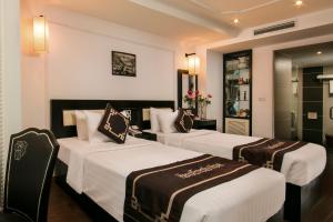 Hanoi Emotion Hotel في هانوي: ثلاثة أسرة في غرفة فندق بجدران بيضاء