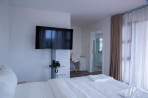 1 dormitorio con 1 cama y TV en la pared en WDC APARTHOTEL - BUEA, en Buea
