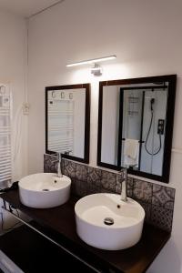 ein Badezimmer mit zwei weißen Waschbecken auf der Theke in der Unterkunft Les chambres de la vallée in Argenton-Château