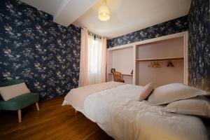 a bedroom with a large bed and a chair at Les chambres de la vallée in Argenton-Château