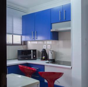 una cocina con armarios azules y taburetes rojos en WDC APARTHOTEL - BUEA, en Buea