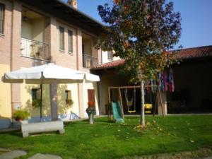a yard with an umbrella and a hammock in front of a building at EL CAVAJER agriturismo-b&b in Revello