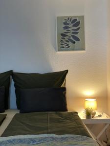 a bed with green pillows and a lamp on a table at Mida Gästehaus in Freiburg im Breisgau