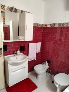 bagno con lavandino, servizi igienici e piastrelle rosse di B&B Il Giardino di Sophie a Villafranca di Forlì