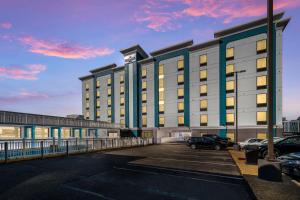 a building with a car parked in a parking lot at Costa Azul Suites Virginia Beach by Red Collection in Virginia Beach