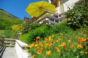 un giardino con fiori d'arancio e un ombrello giallo di GS3 DUPLEX 4 PERS TERRASSE 5mn LUZ 15mn ARDIDEN a Sassis