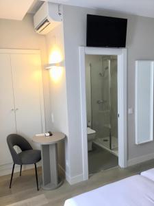 a room with a shower and a table and a chair at Hotel El Águila in Utebo