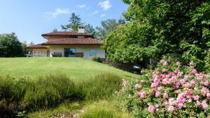 a house on a hill with flowers in the foreground at Lago Maggiore Alture di Stresa casa nel bosco confinante con il Golf des iles Borromées in Brisino