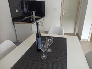 una botella de vino sentada en una mesa con dos copas de vino en Apartmani Drinski biseri Vrhpolje en Vrhpolje