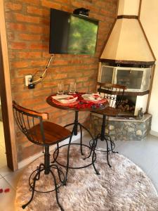 a table with two chairs and a fire place at Chalés Cantinho do Céu in Monte Verde +55 photos
