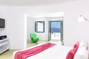 una camera bianca con un letto e una sedia verde di Avant Garde Suites ad Akrotírion