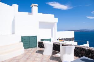 una casa bianca con una porta verde e sedie bianche di Avant Garde Suites ad Akrotírion
