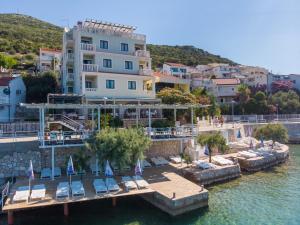 a hotel on the water with chairs and a dock at Hotel Posejdon in Neum