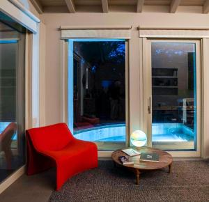 a living room with a red chair and a table at Lago Maggiore Alture di Stresa casa nel bosco confinante con il Golf des iles Borromées in Brisino