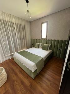 1 dormitorio con 1 cama grande con detalles verdes en Superbe appart cosy résid privée avec piscine en Marrakech