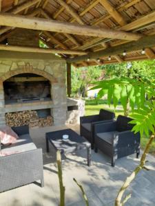 un patio con sofás y una chimenea de piedra. en Guest House Lisina en Poljanak