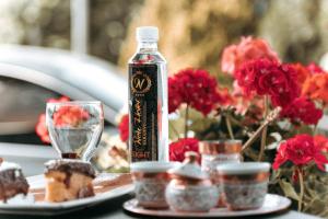 una bottiglia di alcol seduta su un tavolo con fiori rossi di New Hotel a Sarajevo