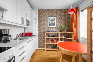 eine Küche mit einem roten Tisch in der Küche in der Unterkunft WeHost Spacious Traveller’s HQ Above Metro @Vilhonvuorenkuja 16 in Helsinki